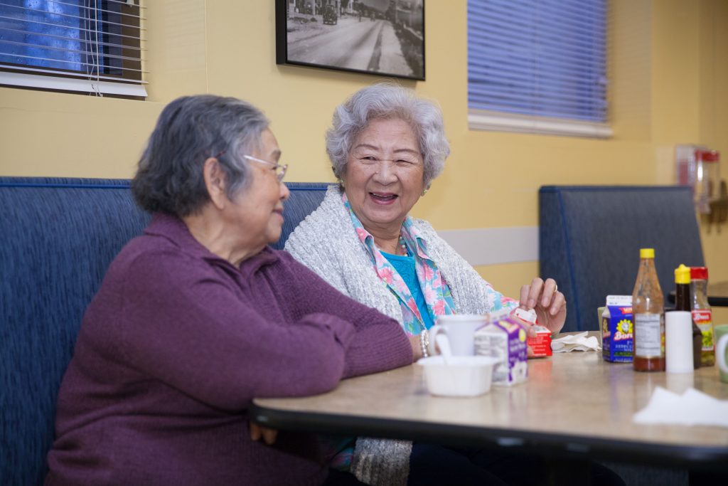 Two older women chat over lunch