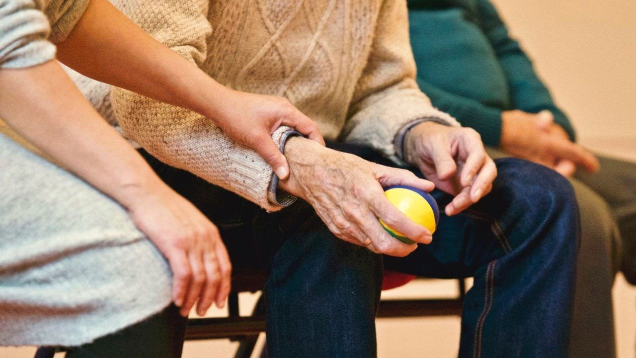 Woman helps man with a physical therapy ball