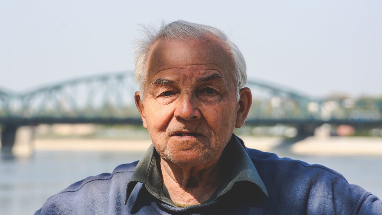Older man near river with bridge