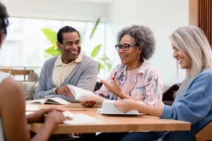 A group of seniors happily discuss papers at a desk.